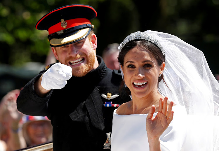 Britain’s Prince Harry gestures next to his wife Meghan as they ride a horse-drawn carriage after their wedding ceremony at St George’s Chapel in Windsor Castle in Windsor, Britain, May 19, 2018.