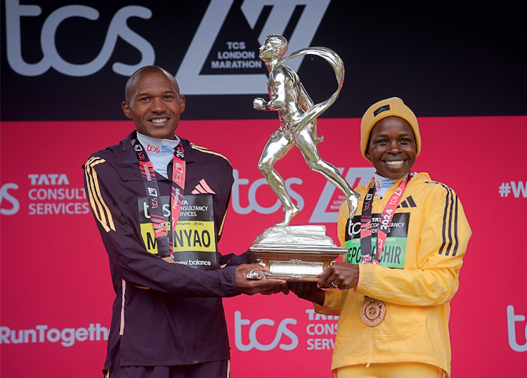 Kenya's Alexander Munyao (L) and Peres Jepchirchir on the podium after winning the 2024 London Marathon in London, Britain, April 21, 2024.