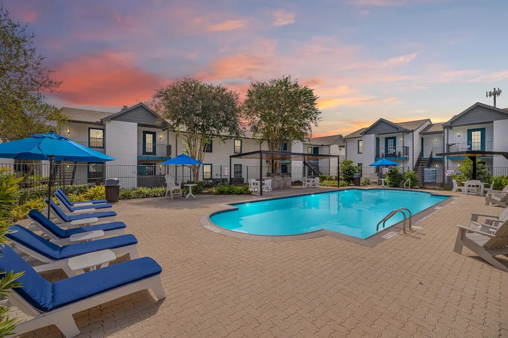 Pine Forest's community pool at dusk with lounge chairs, apartment building in background