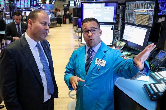 Josh Frydenberg MP, Treasurer of the Commonwealth of Australia, speaks with specialist trader Paul Cosentino on the floor at the New York Stock Exchange (NYSE) File photo.