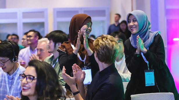 Two girls wearing hijabs clap and smile at each other