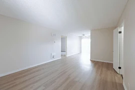 Open concept living and dining area with wood-inspired flooring, white trim, and neutral walls 