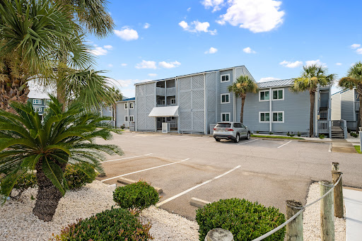 Parking in front of grey building with palm trees in this luxury property for sale in Pensacola ($355,000)