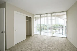 Bedroom featuring large closet, floor to ceiling window, and neutral colored carpet and walls