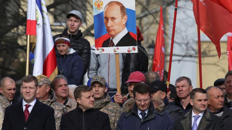 A man holds a portrait of Vladimir Putin during celebrations of the fifth anniversary of Russia's annexation of Crimea in Simferopol, Crimea March 15, 2019