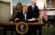 U.S. Vice President Mike Pence stands by as U.S. President Donald Trump signs a proclamation that states the United States recognizes Jerusalem as the capital of Israel and will move its embassy there, during an address from the White House in Washington, U.S., December 6, 2017.