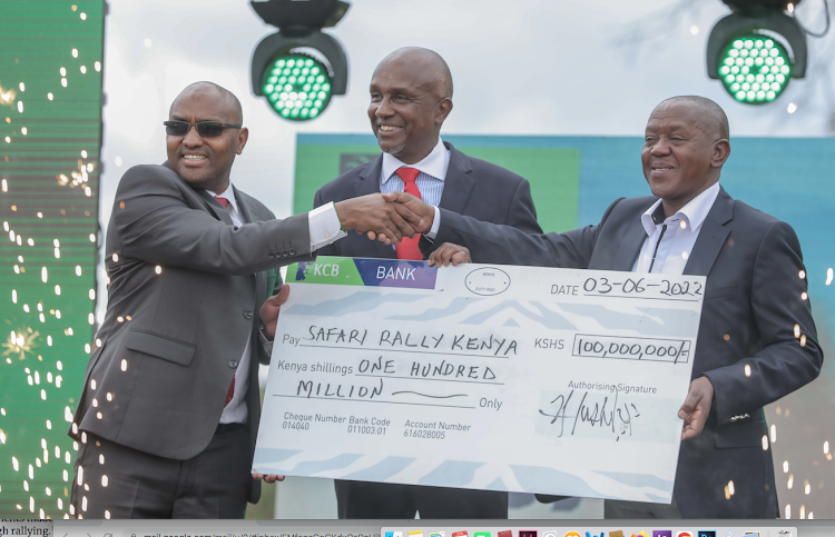 KCB Group CEO, Paul Russo (L) and chairman, Andrew Wambari (C) presents a dummy cheque to WRC Safari Rally CEO, Phineas Kimathi during the launch of KCB 2022 WRC Sponsorship at the Karen Leadership Centre.