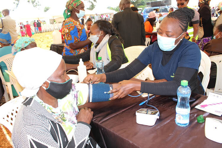 A medic checks woman's blood pressure during a free medical camp in Kigumo on Saturday