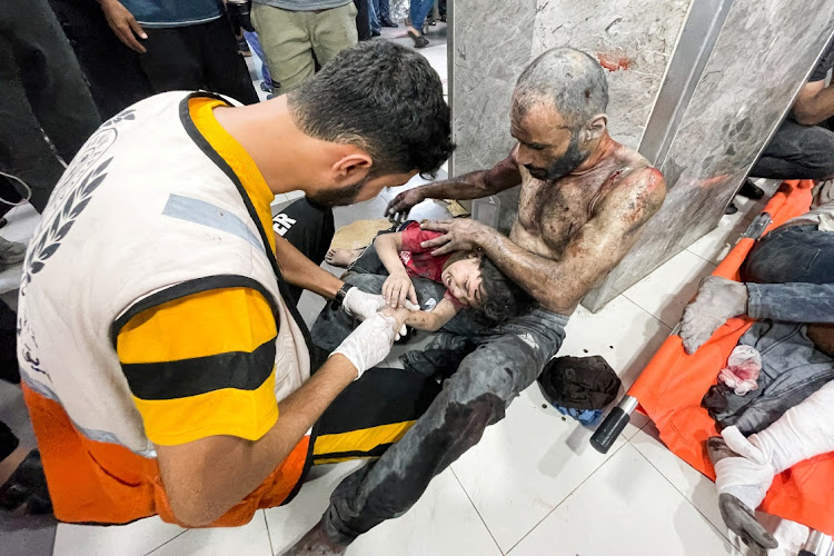 A Palestinian child, who was wounded in an Israeli strike, is assisted next to his father at Shifa hospital in Gaza City on October 23 2023. Piicture: REUTERS/Mohammed Al-Masri