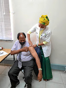 Limpopo health MEC Phophi Ramathuba prepares Bishop  Barnabas  Lekganyane of the Zion Christian Church for his Covid shot. 