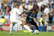 Percy Tau of Club Brugge tries to evade the tackle of Real Madrid's Raphael Varane during their Uefa Champions League tie at the Santiago Bernabeu. 