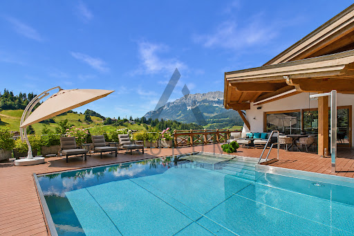 Luxury villa for sale in Ellmau (Austria) - Outdoor swimming pool lounge chairs mountain view