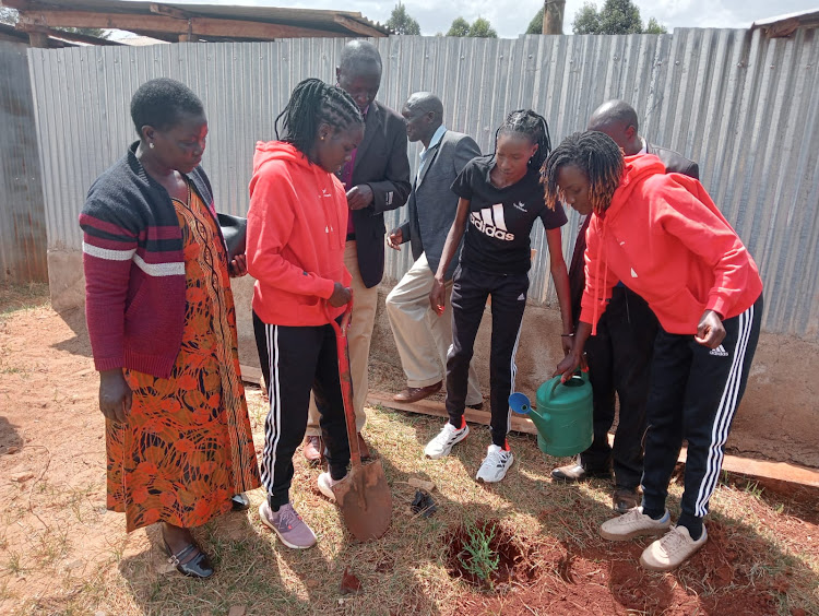 Viola Jeptoo (C) with Agnes Tirop's family members and friends during a tree planting session ahead of the race on Sunday