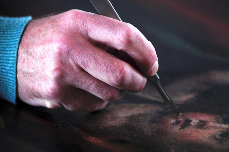 The hand of expert art restorer Ernest Bellingan fixing a work.