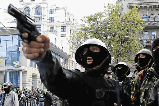 BLOOD IN THE STREETS: A pro-Russian activist aims at supporters of the Kiev government during battles in Odessa Picture: REUTERS