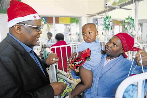 FESTIVE CHEER: BCM mayor Xola Pakati, left, brings some early Christmas cheer to Thandeka Pantsi’s 16-month-old son, Sintu, at Frere Hospital yesterday Picture: MARK ANDREWS