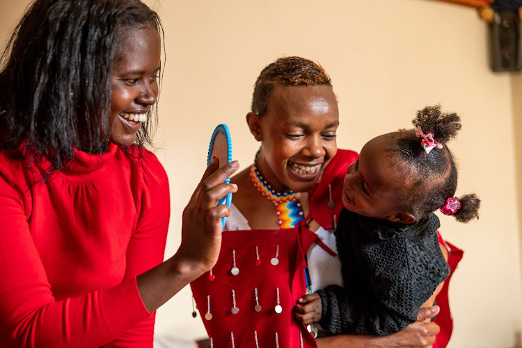 Sylvia and Esther play with two-year-old Mikyela at home in Kajiado town.