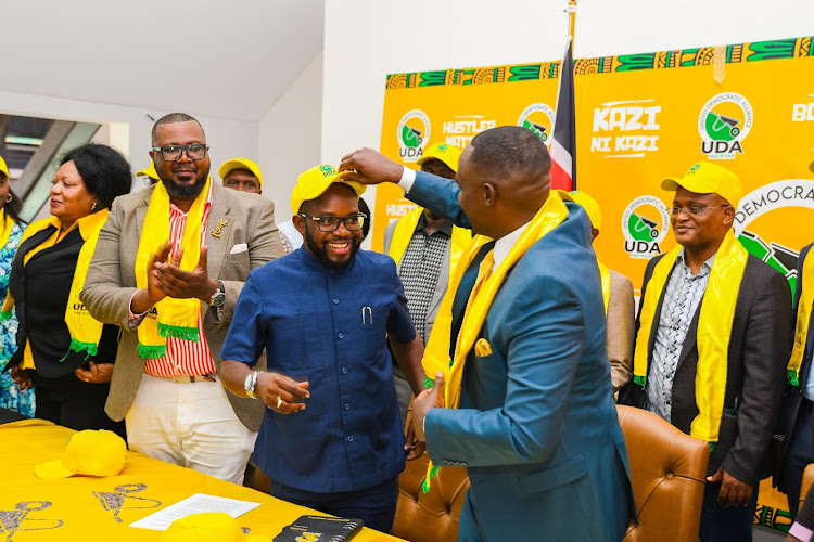 Former Raila Odinga's aide Silas Jakakimba is given a UDA cap by secretary general Cleophas Malala after officially joining the party on March 26, 2024.