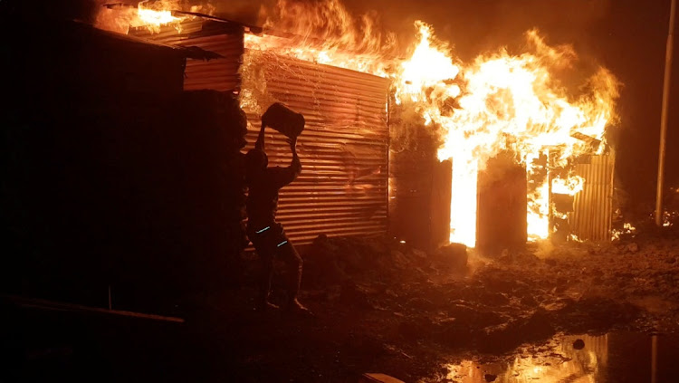 A person attempts to extinguish a blazing building after the volcanic eruption of Mount Nyiragongo near Goma, the Democratic Republic of Congo, in this image from video obtained via social media.