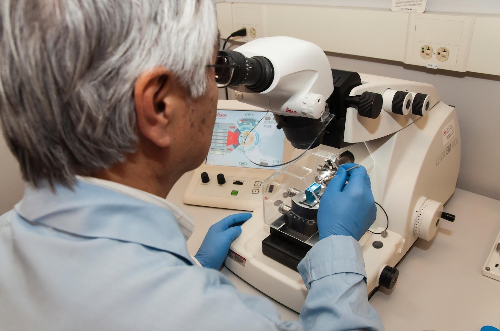 A lab technician looking through a microscope