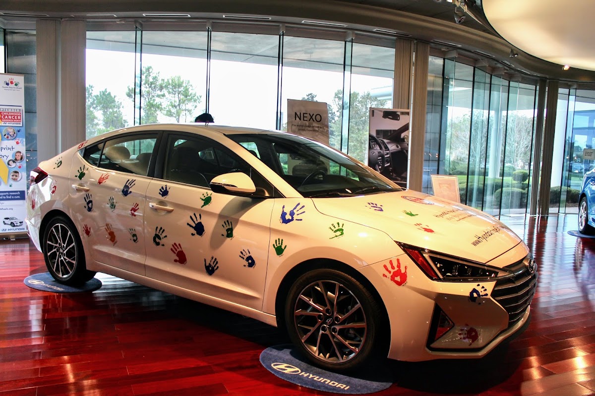 White Hyundai sedan with red, green, blue and purple hand prints all over on display in Hyundai Plant tour in Montgomery