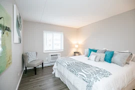 Furnished model bedroom with wood-inspired flooring, a window, and neutral walls 