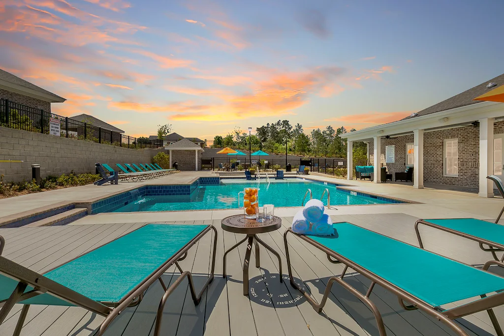 Pool next to clubhouse with light blue lounge chairs at dusk