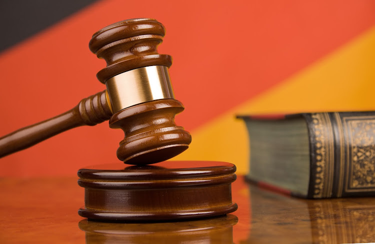 A gavel in court. German flag with shears in the background.