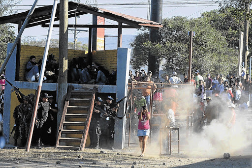 Police officers take cover after family members tried to break into the prison in Comayagua, Honduras, yesterday. A massive fire swept through the overcrowded prison, killing more than people, including many trapped in their cells Picture: REUTERS