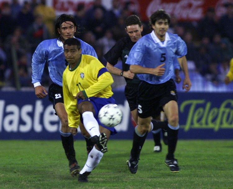 Brazilian Romario kicks the ball as Uruguayan Pablo Garcia (R) and Gonzalo de los Santos give chase during the 200 FIFA World Cup Korea-Japan qualification game in Montevideo.