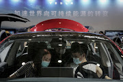 Exhibition staff and attendees look around a Tesla Model 3 at the 18th Central China International Auto Show on August 13 in Wuhan, Hubei, China.