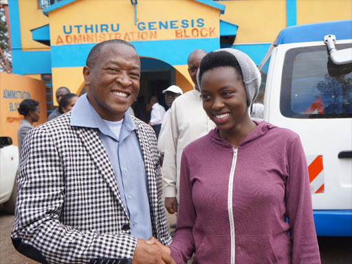 Uthiru Genenis Primary School head teacher James Gicheha congratulates Ann Wangare, who got 424 marks in KCPE and scored 99 per cent in English.