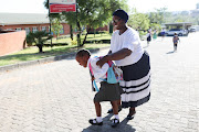 Grade 4 maths and natural science teacher Nurse Raleano helps an upset grade 1 pupil get to class at Cosmo City Primary.