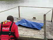 A diver from the police search and rescue unit stands over the body of 68-year-old Thanalatchmee Durugan, who was killed and dumped in a dam at the Silverglen nature reserve, south of Durban. 