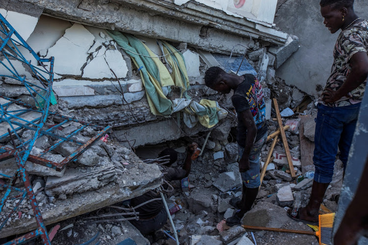 People look for survivors at a house destroyed following a 7.2 magnitude earthquake in Les Cayes, Haiti August 14, 2021.