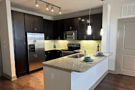 Kitchen with a breakfast bar with stone countertops, dark wood cabinets, and stainless steel appliances 