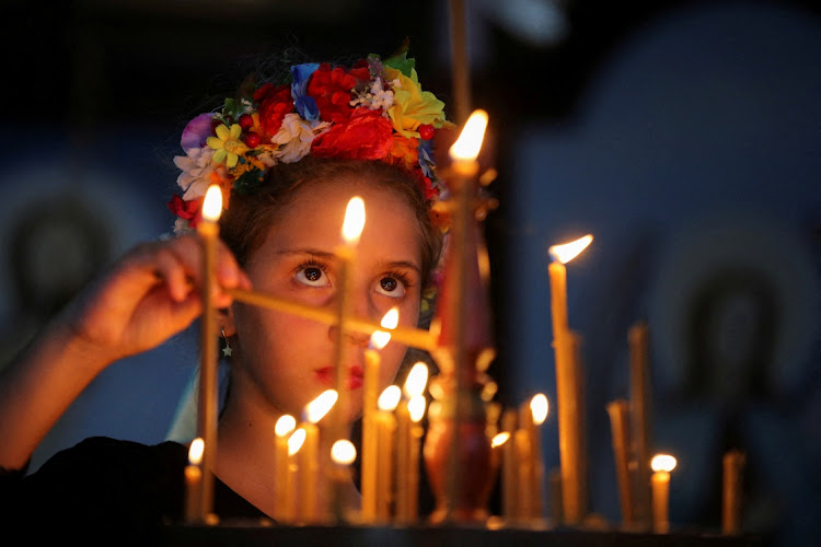 A girl descendant of Ukrainian immigrants lights candles during a mass at a Ukrainian Orthodox church, after the Russian invasion of Ukraine, in Canoas, Rio Grande do Sul state, Brazil March 3, 2022.