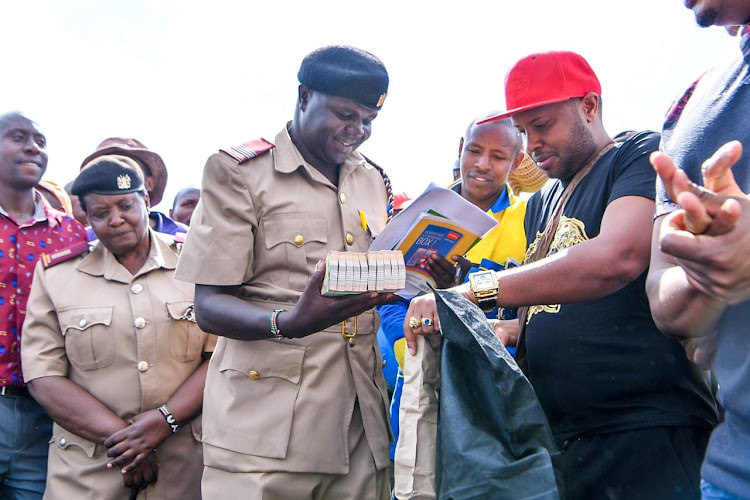 Political and youth affairs advisor at the office of the Vice President George Theuri presents the donation to traders affected by fire at Gikomba market