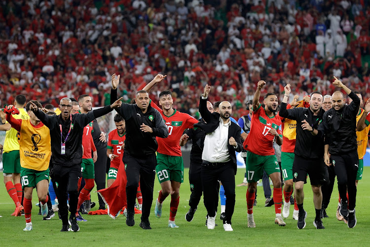 Morocco coach Walid Regragui, centre in a white shirt, leads his team in celebrations after their World Cup semifinal victory against Portugal at Al Thumama Stadium in Qatar on December 10 2022.