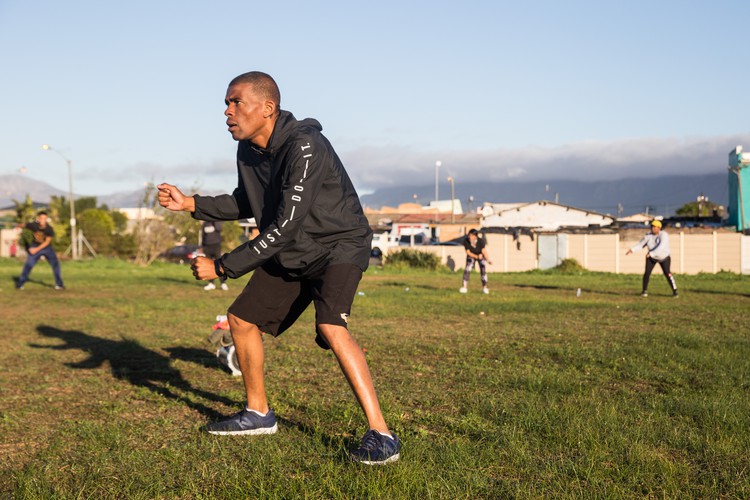 Glenn Hans ends his fitness routine on the field, demonstrating a 'mop the floor' bodyweight exercise.