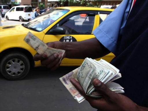 A fuel attendant handles money at a petrol station in Nairobi, March 15, 2011. /REUTERS