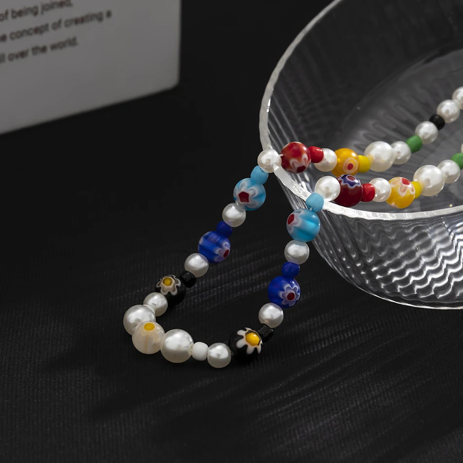 Collier de perles avec couture de petites fleurs et glaçage coloré. Un accessoire élégant qui sublime votre style et ajoute de la couleur à toute tenue.