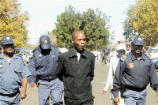 FLASHBACK: Police escort former Ituteng Trust student Simphiwe Ncoguthu after his arrest in Protea this week. Pic. Veli Nhlapo. 15/05/2007. © Sowetan.