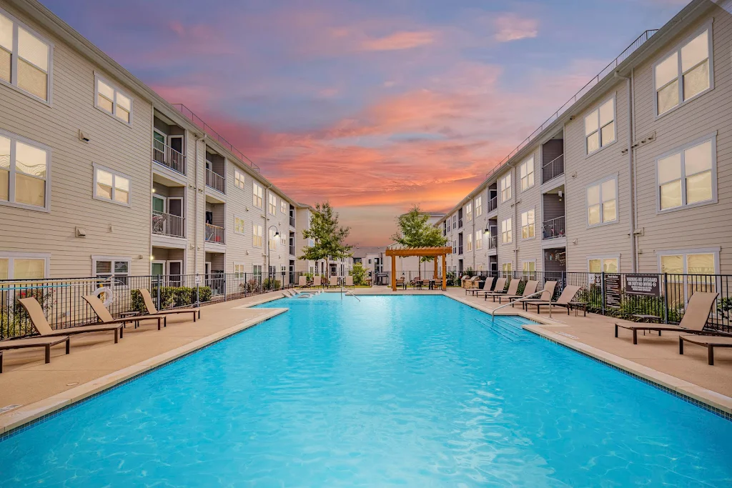 Urban Oaks' large swimming pool at dusk with a sundeck featuring lounge chairs