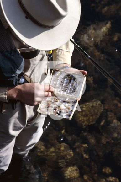 Fly fisherman selecting fly from lure box, Sun Valley, Idaho