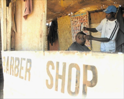 UNDERGROUND THREAT: A man gets a haircut at a barber shop in Thembelihle informal settlement near Lenasia, south of Johannesburg, where residents are living on a layer of dolomite.