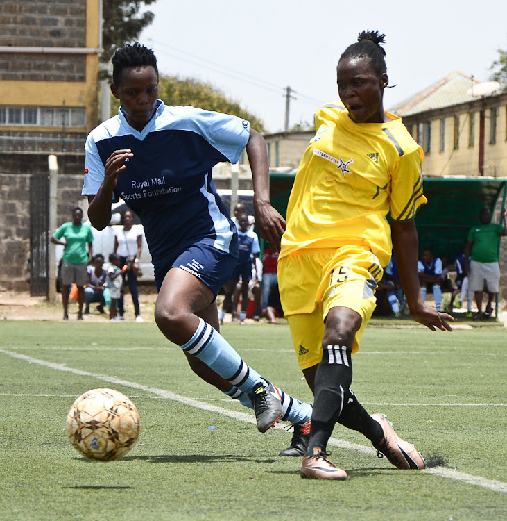 Vihiga Queens' Myline Awuor passes the ball under pressure from Makolanders' Faridah Nyarotso during a WPL match