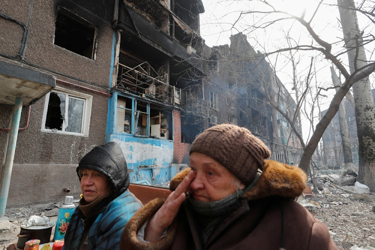 Residents Lyubov Ostranitsa, 76, and Svetlana Mechetnaya, 60, who sought refuge in the basement of a damaged apartment building sit on a bench in a courtyard in the besieged southern port city of Mariupol, Ukraine, on March 25 2022.