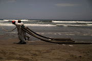 Workers clean up an oil spill following an underwater volcanic eruption in Tonga, in Ancon, Peru January 25, 2022. 