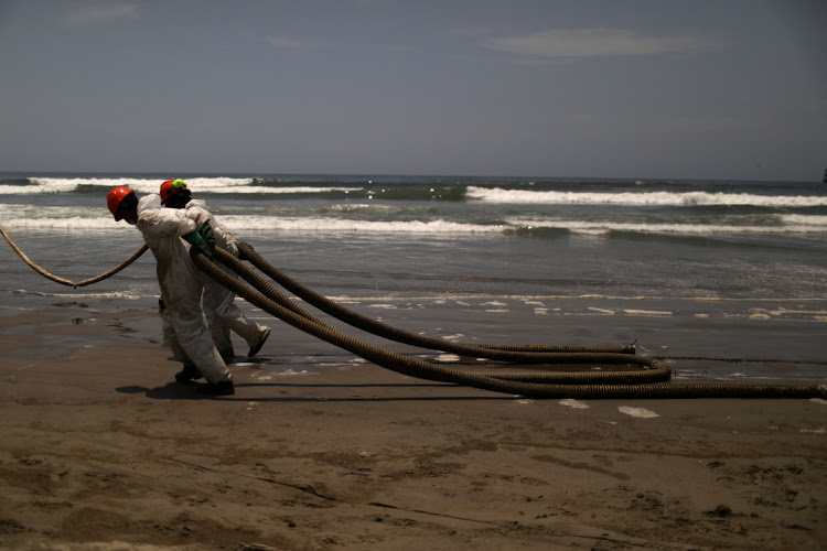 Workers clean up an oil spill following an underwater volcanic eruption in Tonga, in Ancon, Peru January 25, 2022.